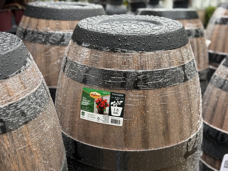 large brown and black plastic barrel planters upside down in garden center in rain