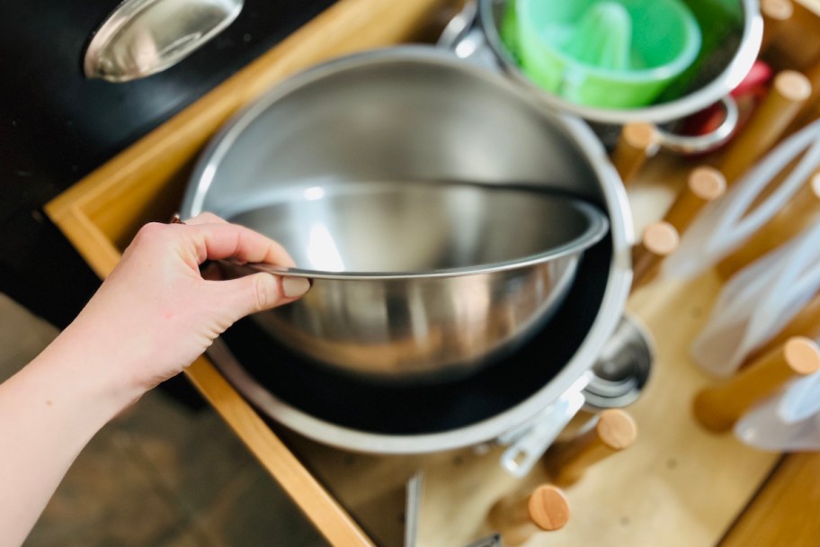 hand pulling stainless steel bowl out of drawer