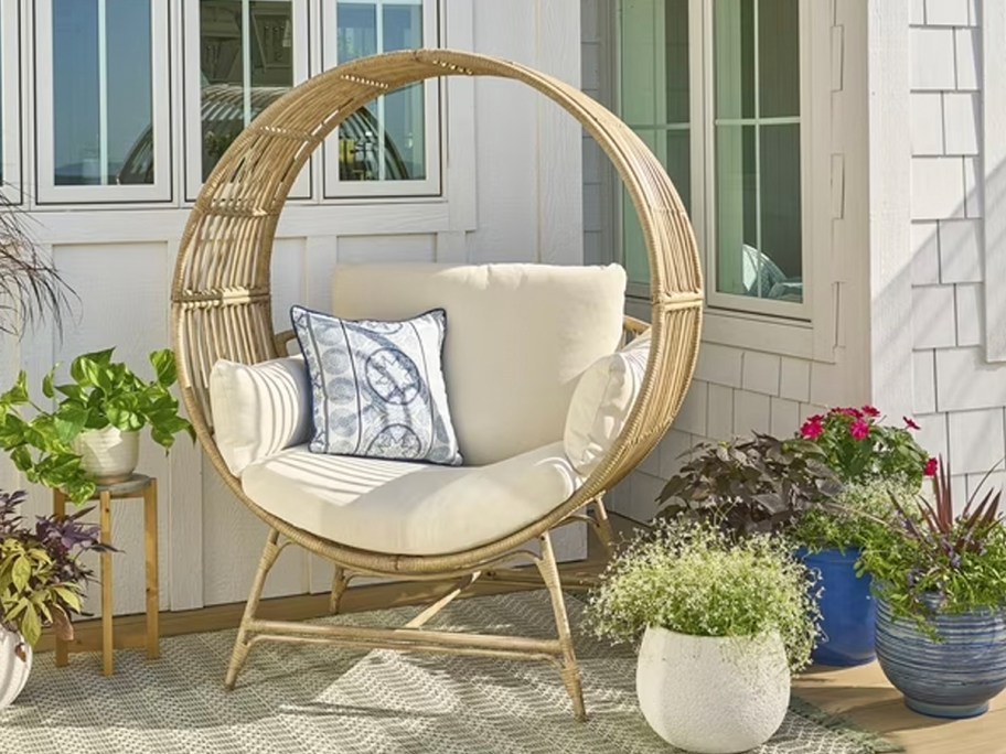 tan round egg chair with white cushions on porch