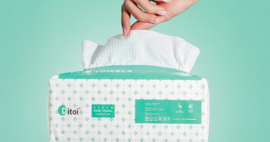 hand pulling disposable face towel out of package