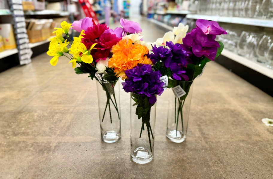 faux flower stems displayed in clear tall glass vases displayed on the floor at dollar tree