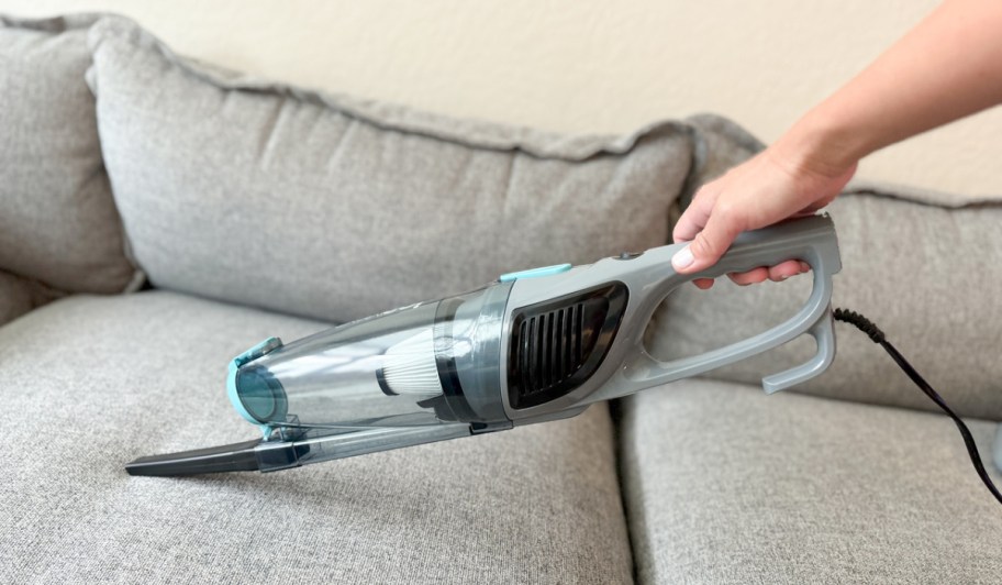 person using an ionvac hand vac on couch