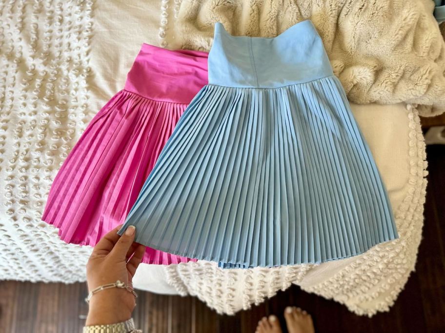blue and pink pleated skirts on bed 