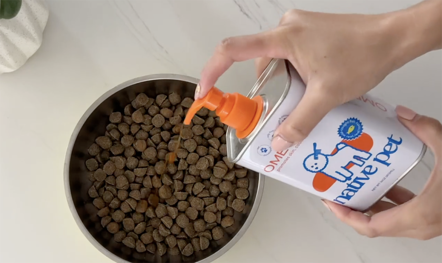 person pumping omega oil into dog food