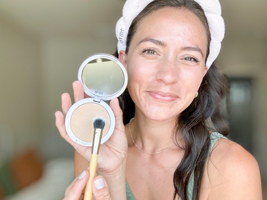 woman holding tarte foundation and brush