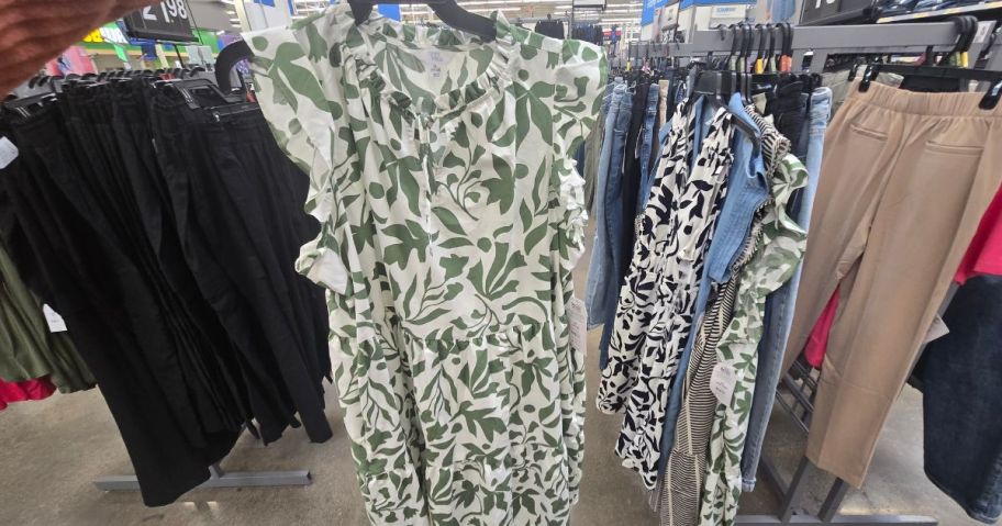 person holding green printed flutter sleeve dress in store