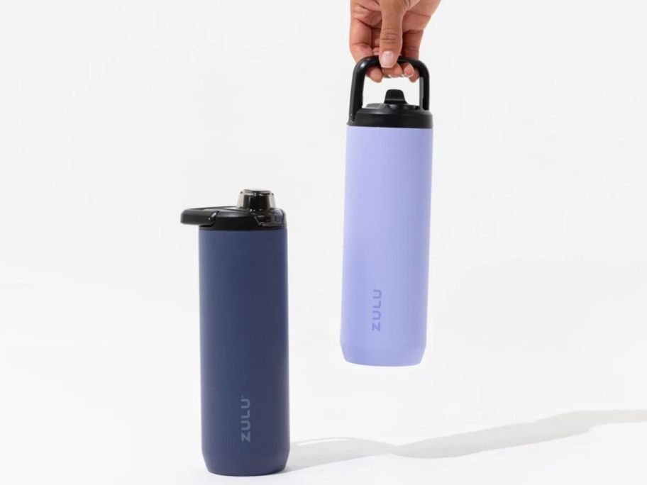 hand holding a light blue zulu water bottle next to another dark blue zulu water bottle