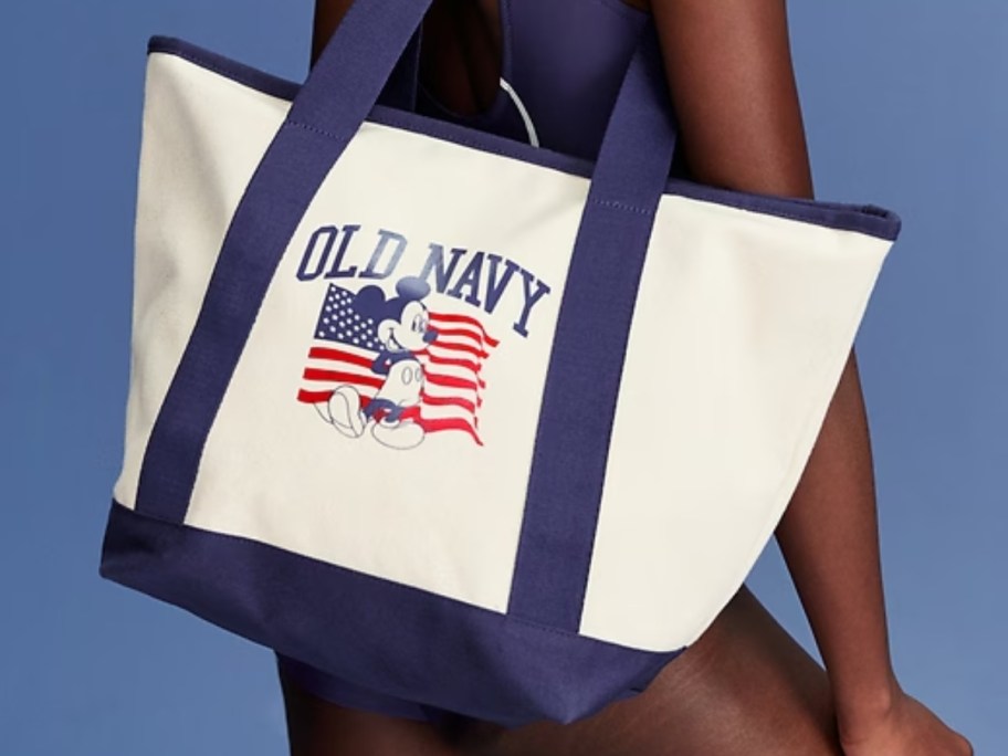 woman carrying a large canvas Old Navy and Mickey Mouse tote bag