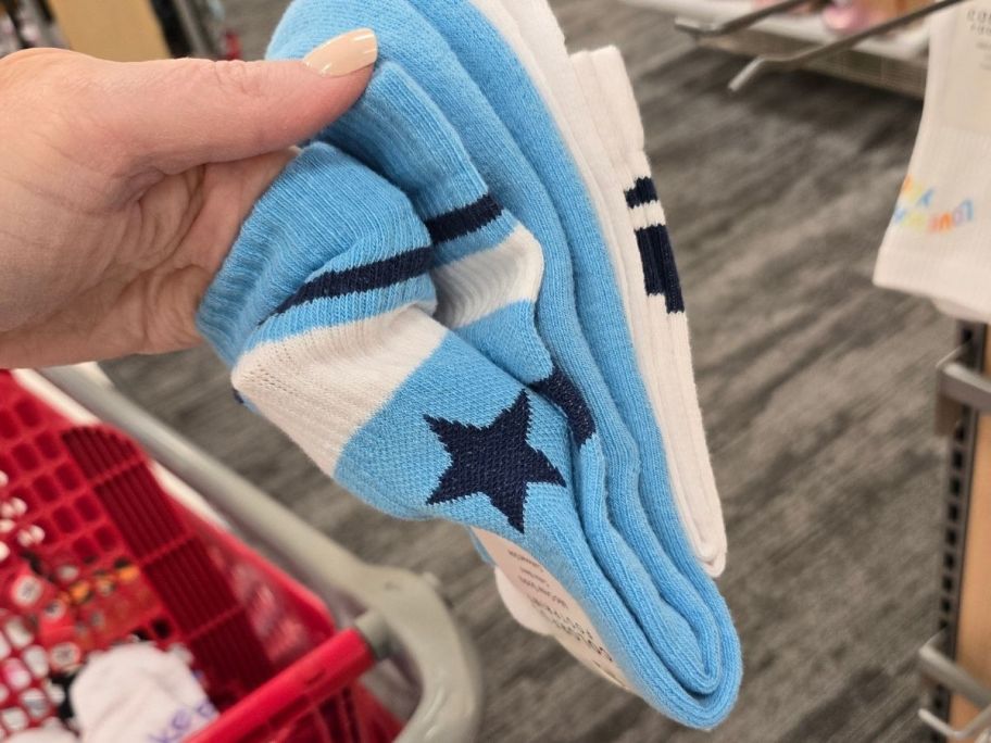 a womans hand holding a 2-pack of graphic crew socks