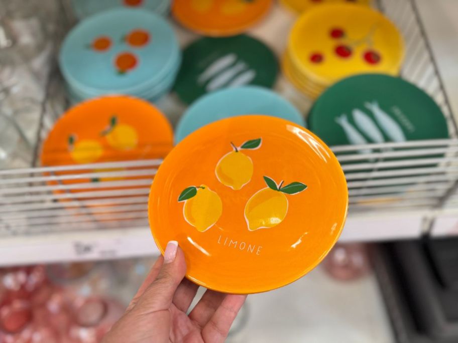 A person holding a small orange plate with lemons on it 