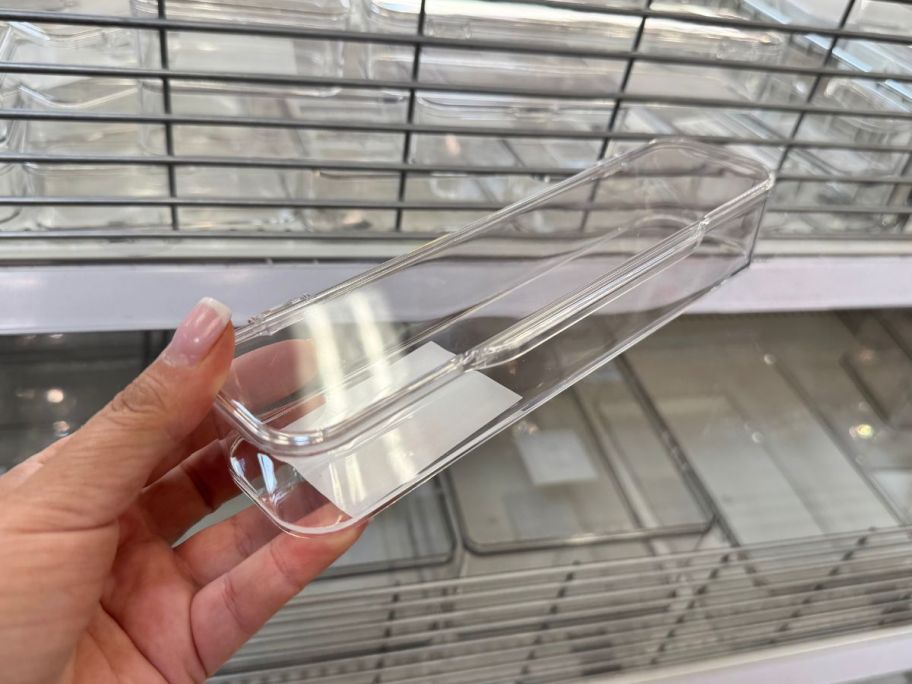 A person holding a small , clear, plastic container