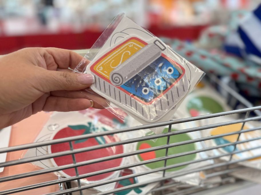 A person holding a sponge shaped like a sardine can