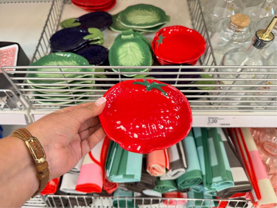 A person holding a ceramic tomato plate