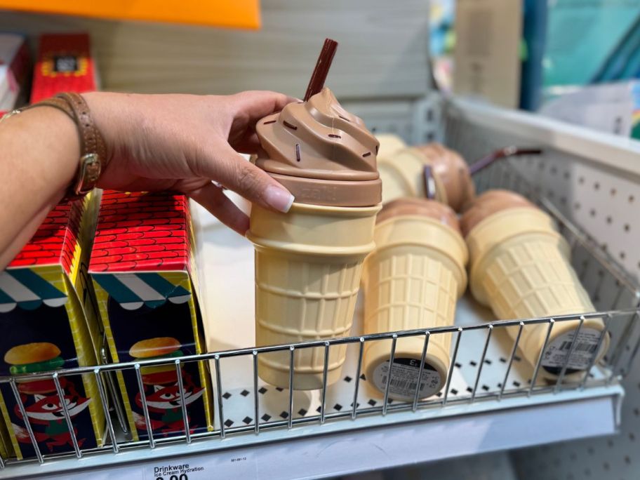 A person holding a cup shaped like an ice cream cone 
