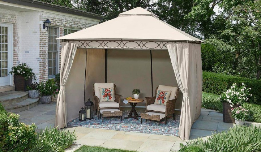Gazebo with curatins closed with two chairs displayed underneath