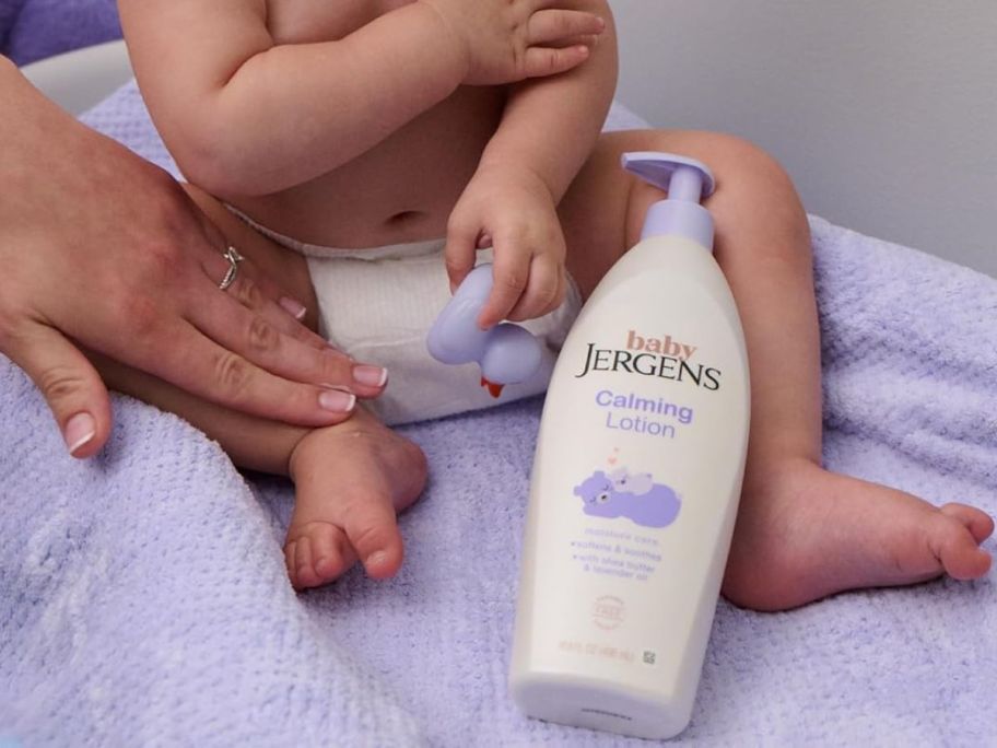 A baby with a bottle of Jergen's Baby Calming lotion 