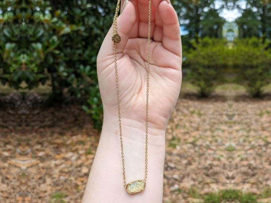Hand holding a Kendra Scott inspired necklace from Amazon