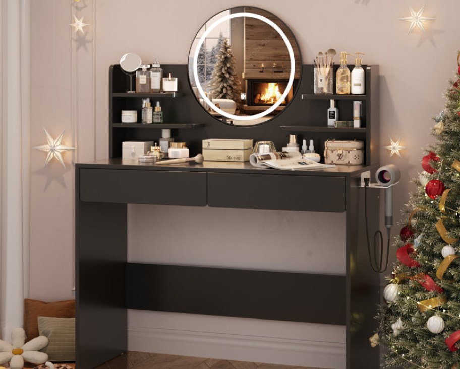 black vanity with round mirror displayed with items on it and a hair dryer rack