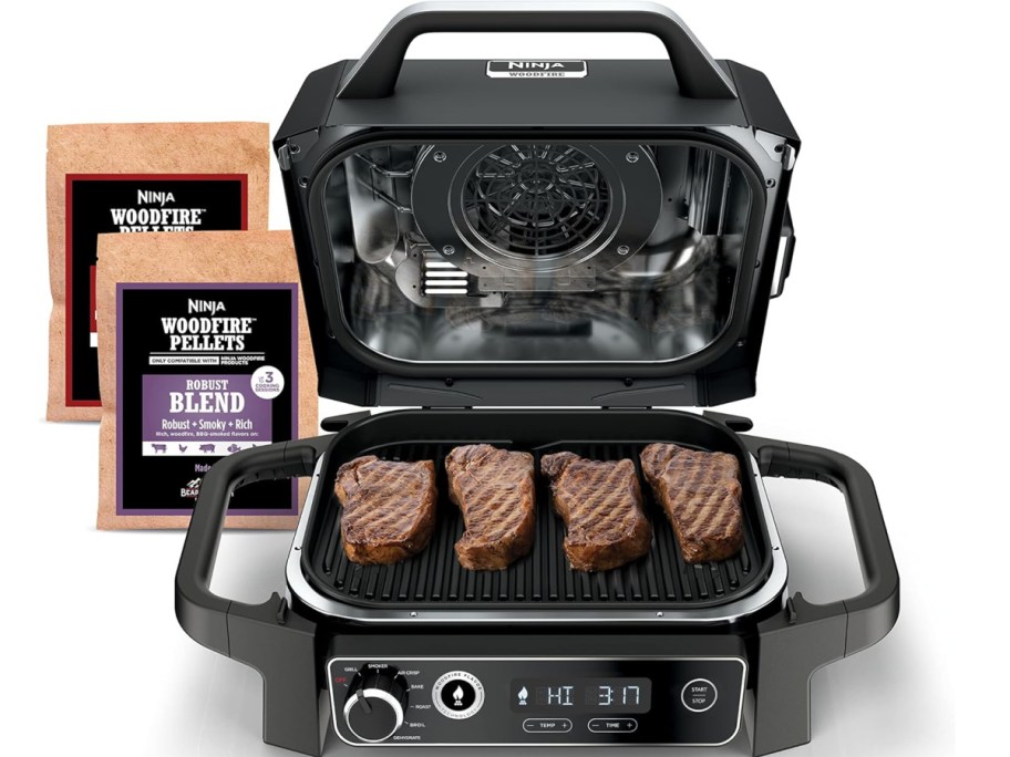 Ninja wild fire with 4 steaks on it and 2 different blends of wood behind it 
