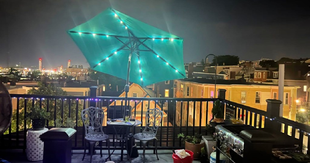 Lit up blue umbrella displayed on outdoor balcony surrounded by patio furniture
