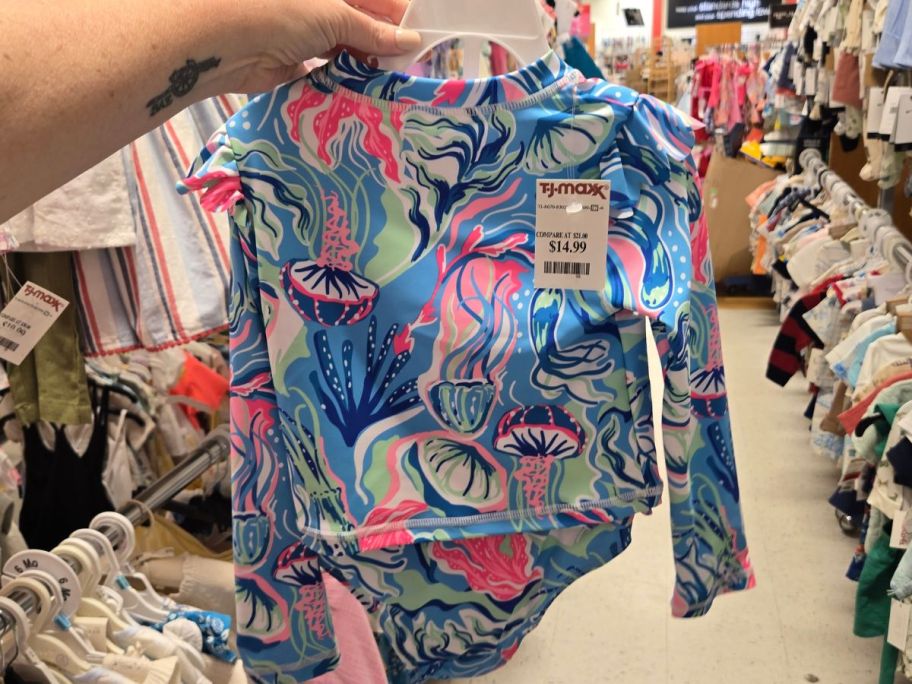 Hand holding a toddler girl's swimsuit at TJ Maxx