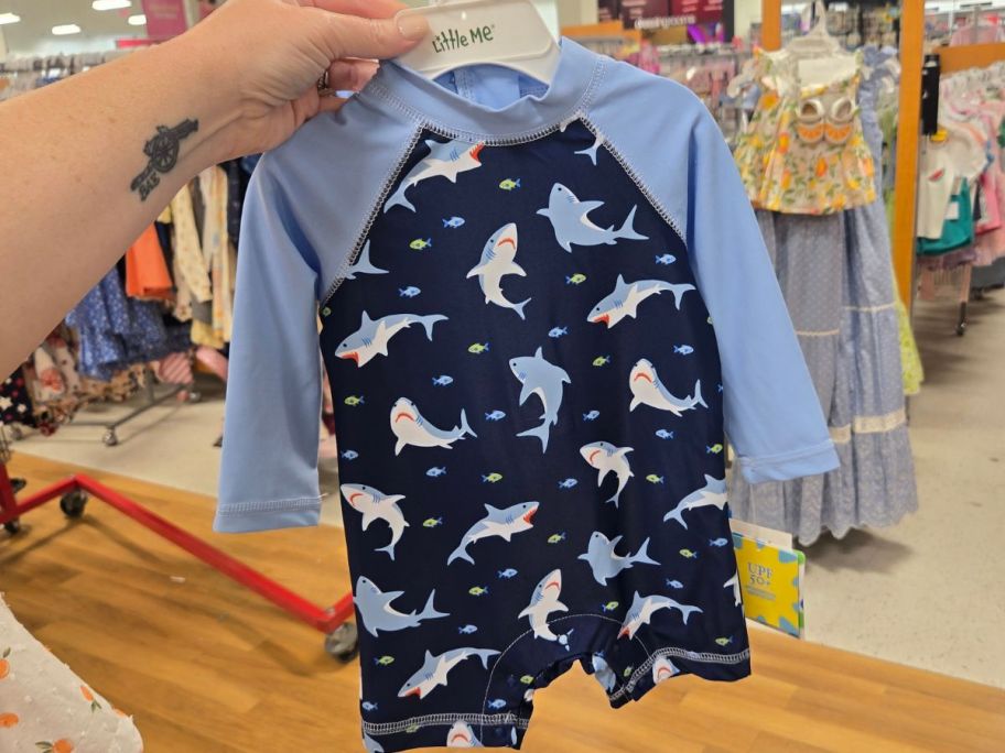 Hand holding a shark rashguard at TJ Maxx