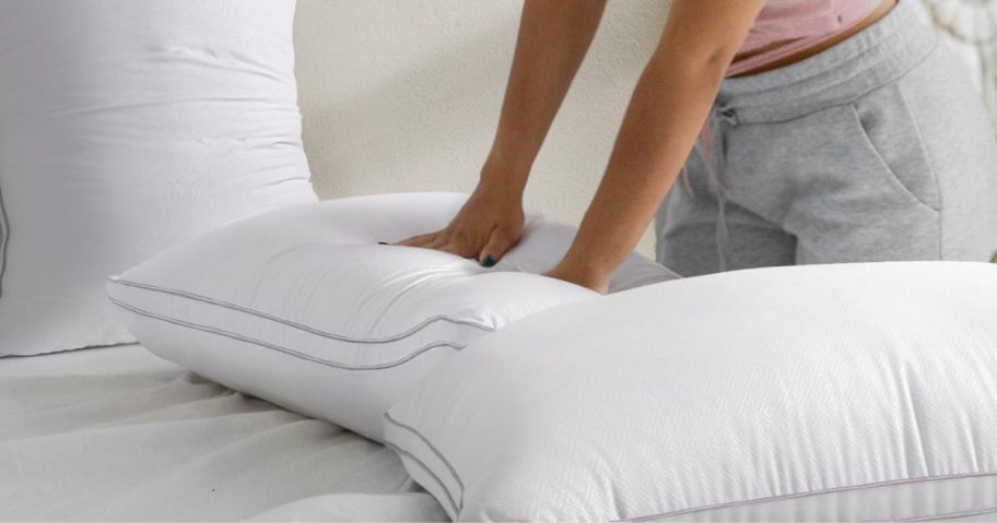 A woman testing the firmness of a pillow with her hands