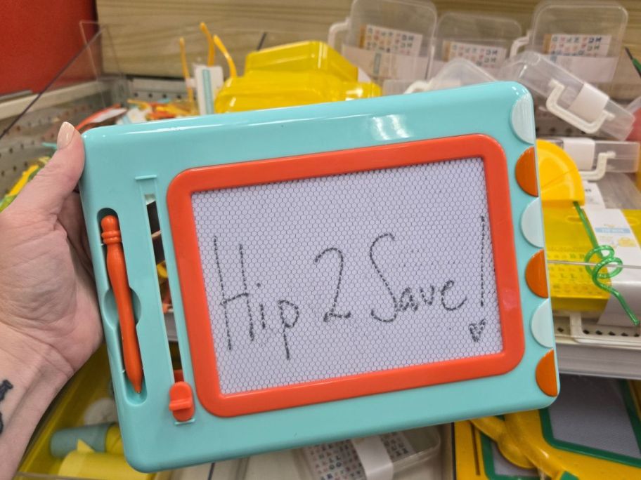 a green and orange Magic Drawing Board with hip2save written on it in hand in store
