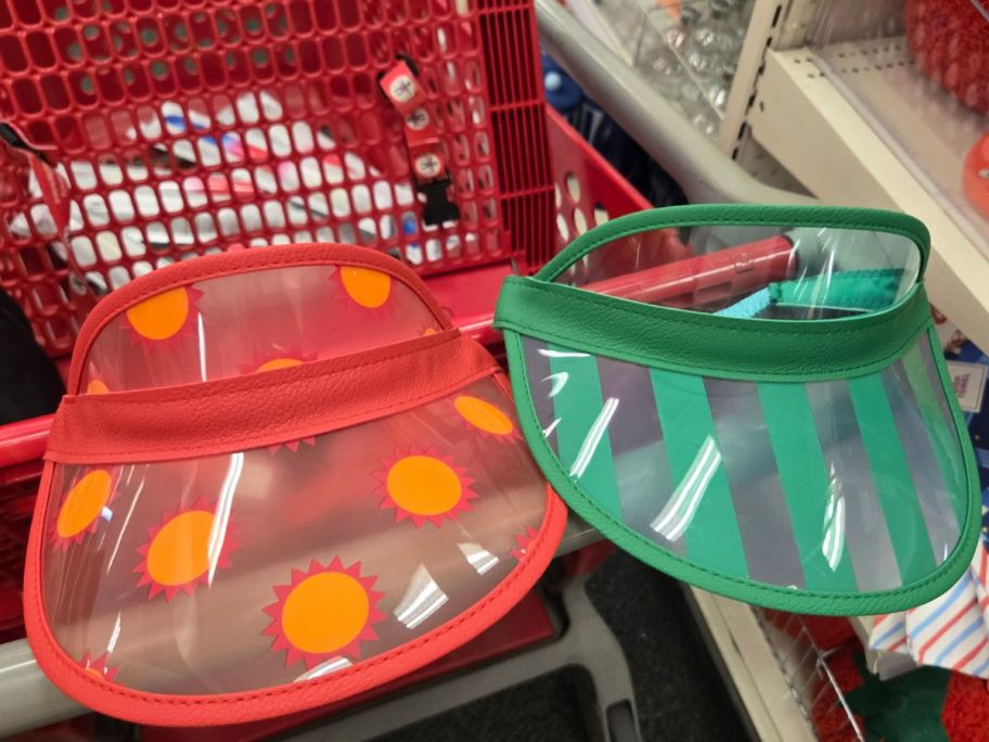 an orange sunshine decorated and a green striped kids visor in cart in store