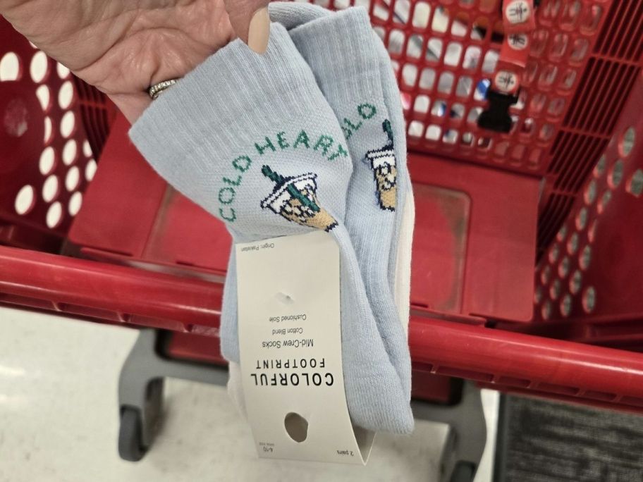 a womans hand holding a 2-pack of graphic crew socks