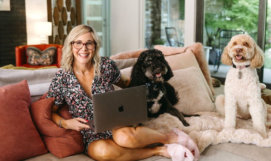 woman with laptop on lap sitting on couch with dogs