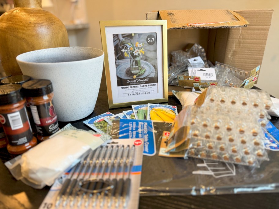 gold frame, planter, mini glass bottles, pens, and more supplies next to cardboard box