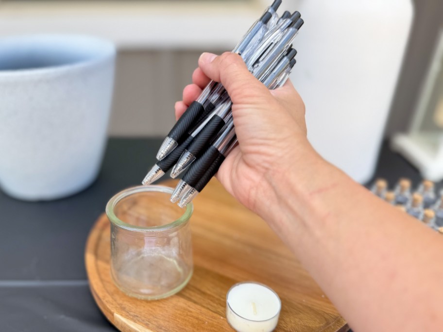 hand holding many pens putting into jar