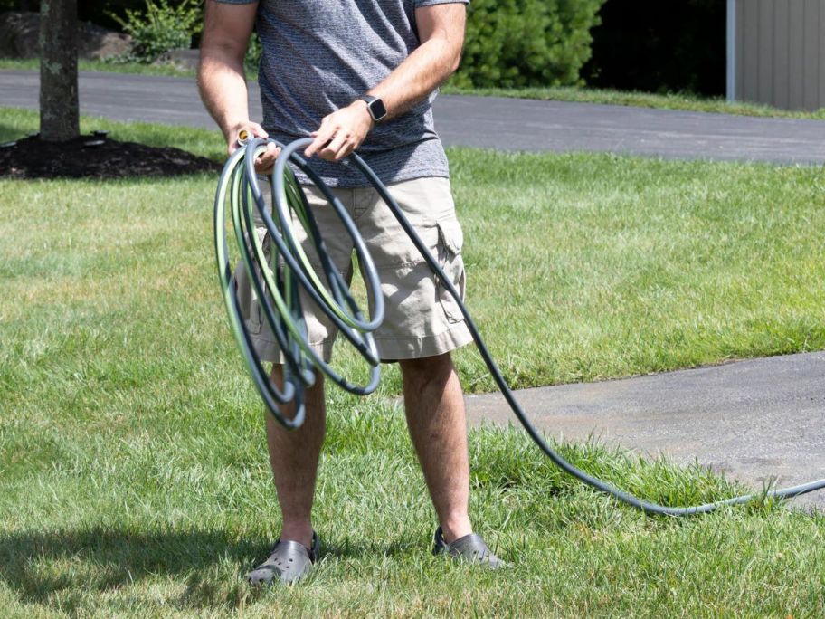 man unraveling Zero-G NXT 50' Premium-Duty Kink Free Hybrid Polymer Hose out on lawn
