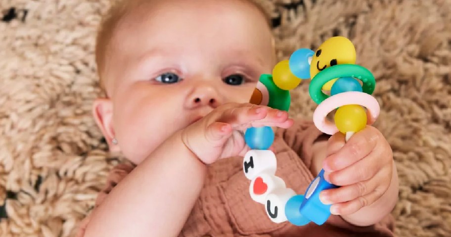 bbay holding an infantino busy beads friendship teether