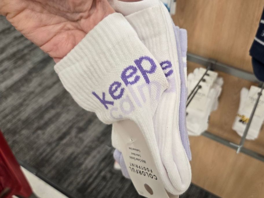 a womans hand holding a 2-pack of graphic crew socks
