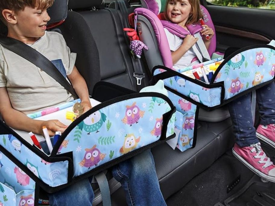 two kids using kids travel trays in car