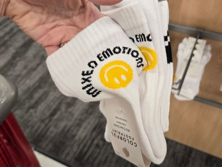 a womans hand holding a 2-pack of graphic crew socks
