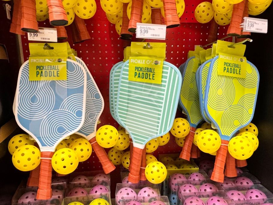 three Pickle O'Joe Paddle & Ball Sets hanging in store