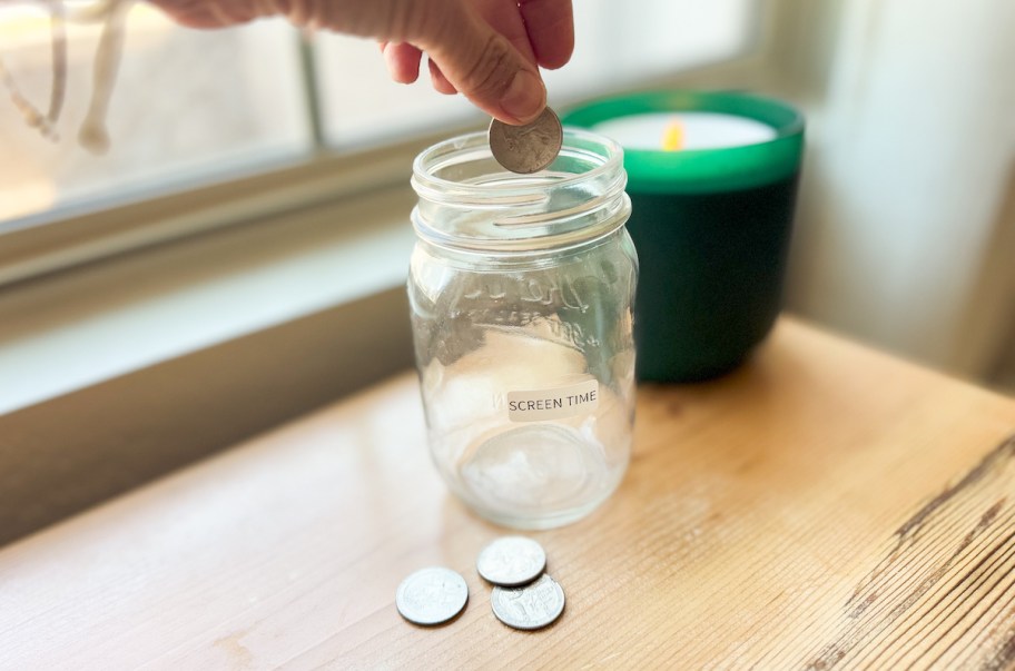hand putting quarter into screen time jar