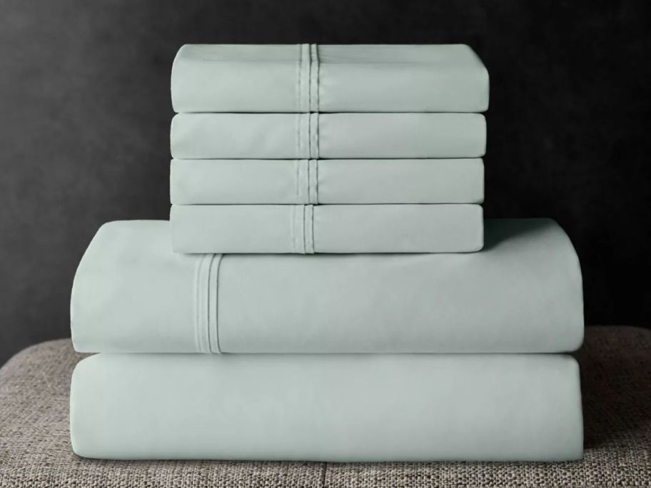 light green Member's Mark Hotel Premier Collection 700-Thread Count Sheet Set stacked on bed