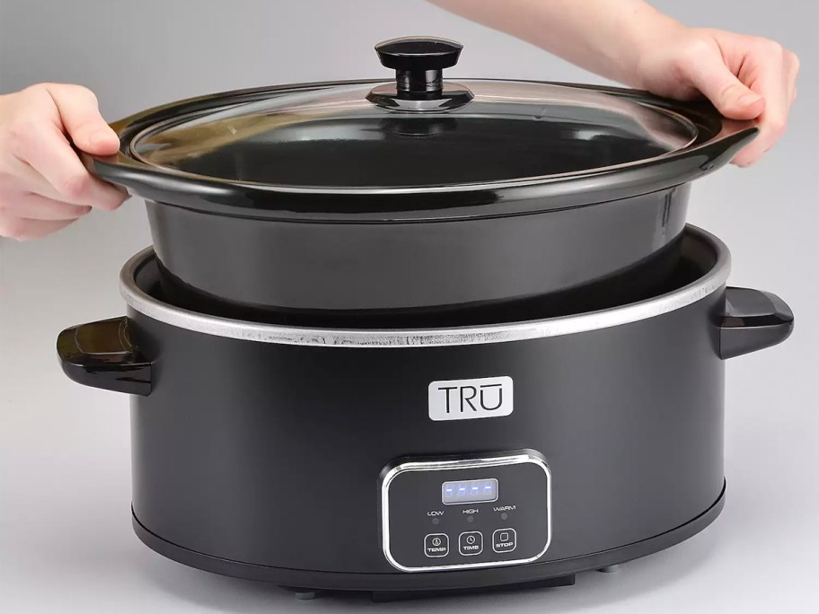 hand taking pot out of slow cooker