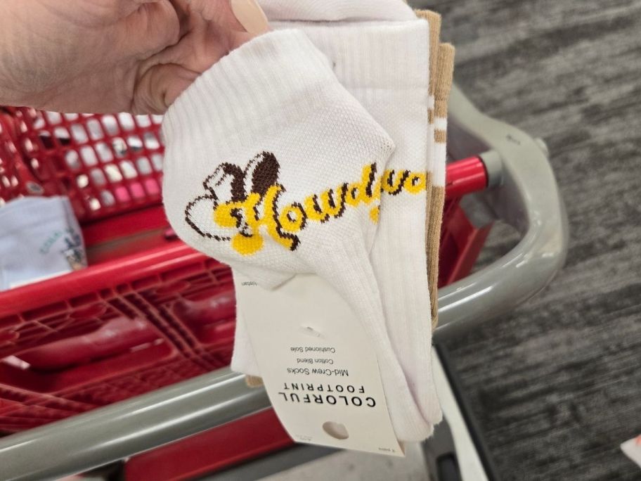 a womans hand holding a 2-pack of graphic crew socks