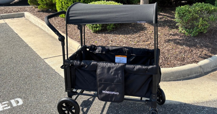 a black Wonderfold stroller wagon with the canopy up in a driveway