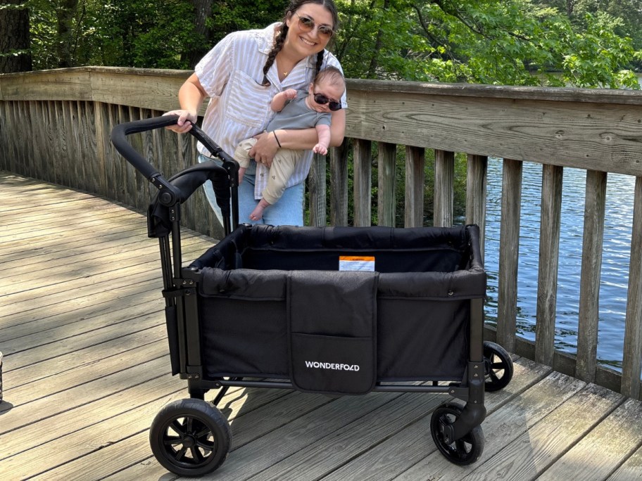 woman holding a baby next to a black Wonderfold stroller