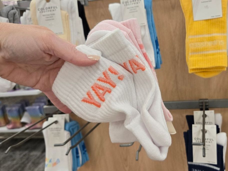a womans hand holding a 2-pack of graphic crew socks